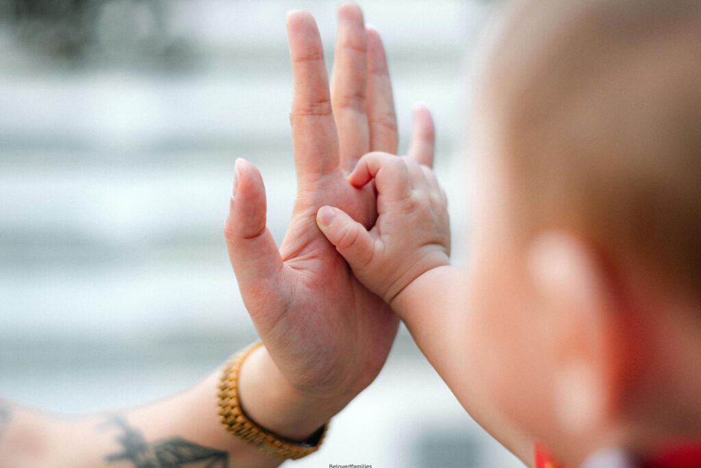 A baby attempting to hold on a mom's hand