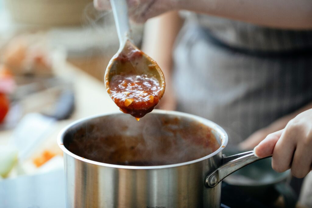 Crop women cooking sauce together
