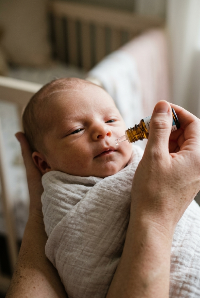 Mother giving newborn baby simethicone gas relief drops